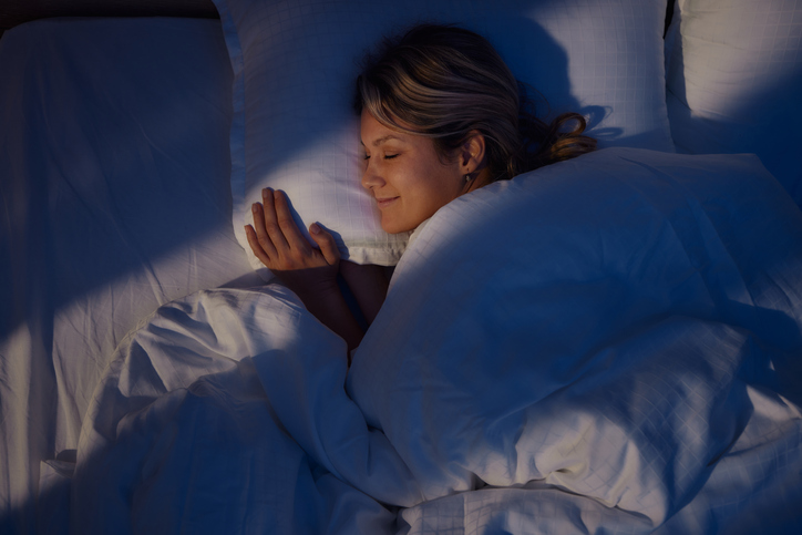 Above view of smiling woman sleeping in bed.